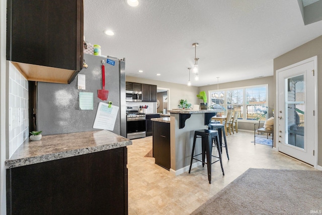 kitchen with hanging light fixtures, a kitchen bar, appliances with stainless steel finishes, and light countertops