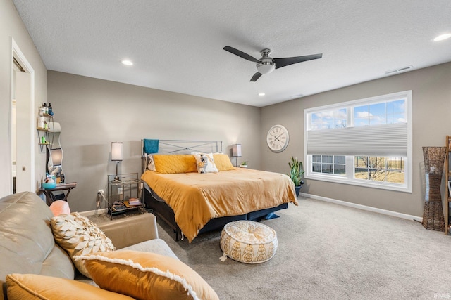 carpeted bedroom featuring a ceiling fan, visible vents, a textured ceiling, and baseboards