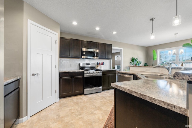 kitchen featuring hanging light fixtures, appliances with stainless steel finishes, light countertops, and a sink