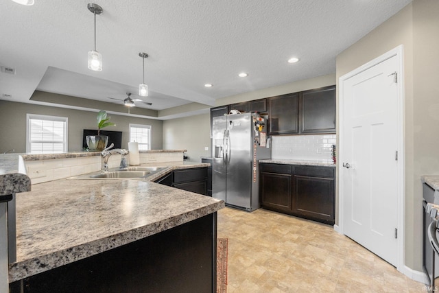 kitchen featuring a raised ceiling, stainless steel refrigerator with ice dispenser, a sink, and light countertops