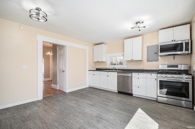 kitchen with stainless steel appliances, dark countertops, white cabinetry, and a sink