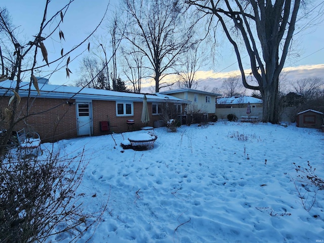 snow covered property featuring brick siding