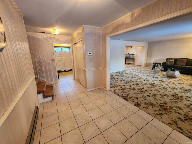 hallway featuring ornamental molding, baseboard heating, light tile patterned flooring, and light colored carpet