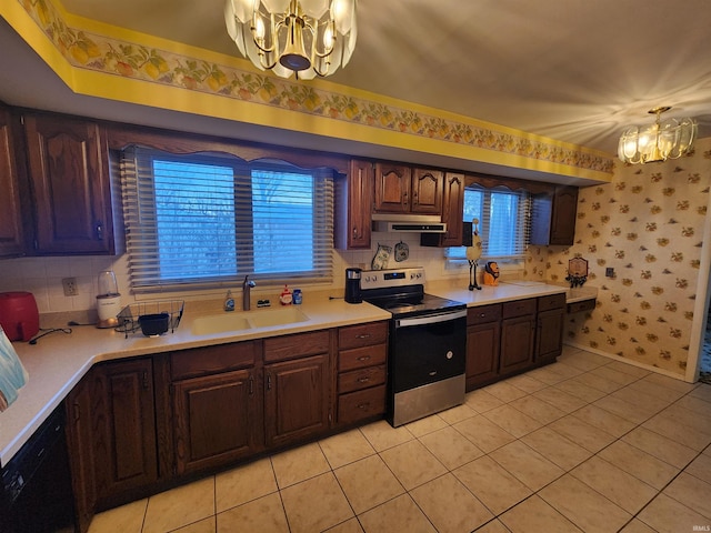 kitchen featuring a notable chandelier, stainless steel electric stove, light countertops, a sink, and wallpapered walls