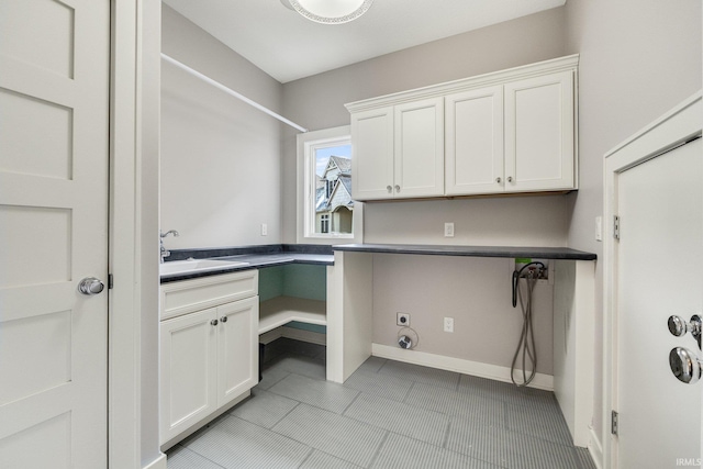 washroom with baseboards, a sink, cabinet space, and electric dryer hookup