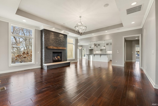 unfurnished living room with dark wood-type flooring, a raised ceiling, visible vents, and a fireplace