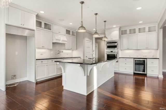 kitchen featuring glass insert cabinets, dark countertops, white cabinets, and a kitchen island