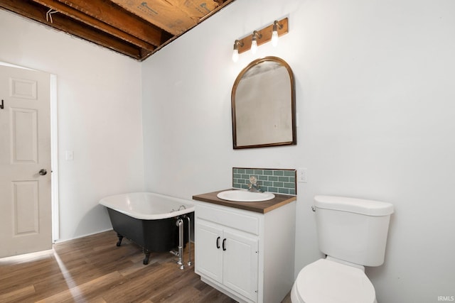 full bathroom with a freestanding tub, toilet, wood finished floors, vanity, and decorative backsplash