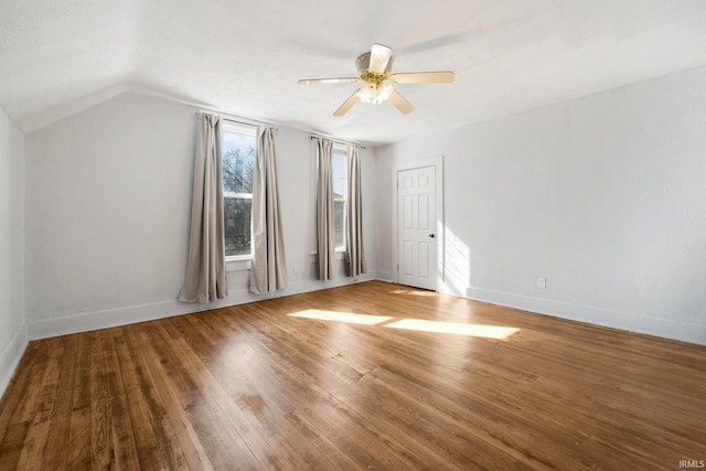 spare room with ceiling fan, vaulted ceiling, baseboards, and hardwood / wood-style flooring