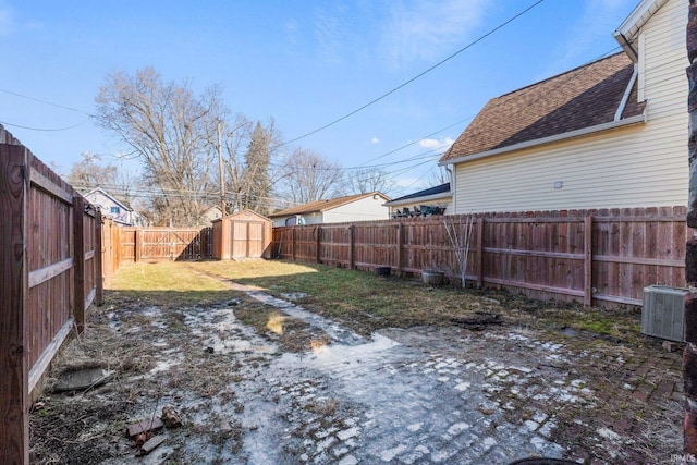 view of yard featuring a fenced backyard, a storage unit, central AC, and an outbuilding