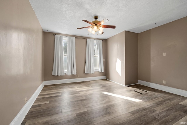 unfurnished room featuring visible vents, ceiling fan, a textured ceiling, wood finished floors, and baseboards