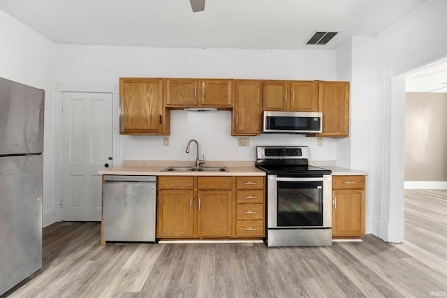 kitchen featuring stainless steel appliances, light countertops, visible vents, light wood-style floors, and a sink