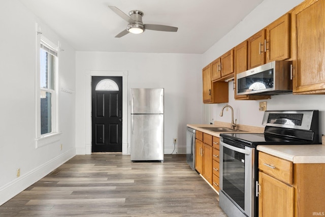 kitchen featuring stainless steel appliances, light countertops, a sink, and wood finished floors