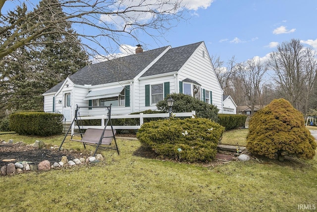 view of front of property featuring roof with shingles, a chimney, and a front yard