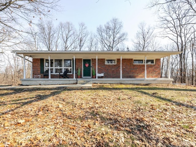 single story home featuring a porch, brick siding, and a front lawn