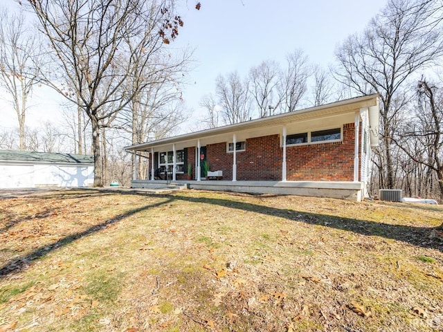 single story home with a porch, a front yard, brick siding, and central AC