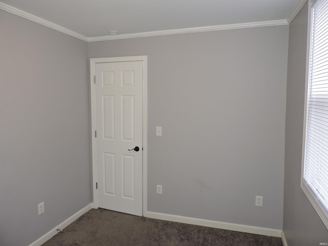 spare room with baseboards, crown molding, dark carpet, and a wealth of natural light