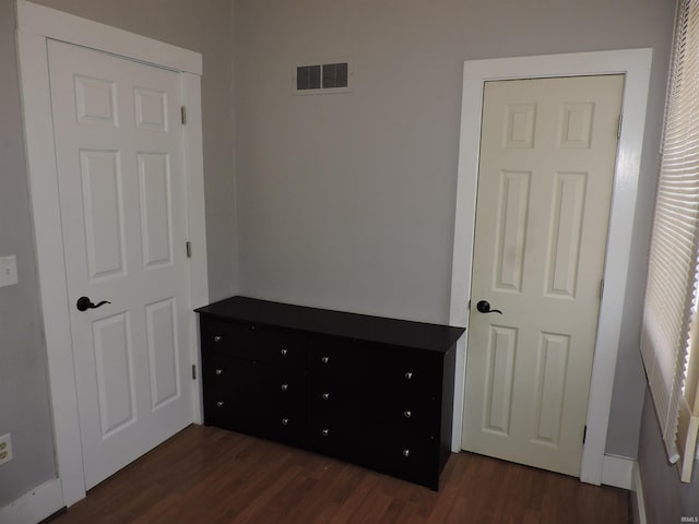 unfurnished bedroom with visible vents and dark wood-type flooring