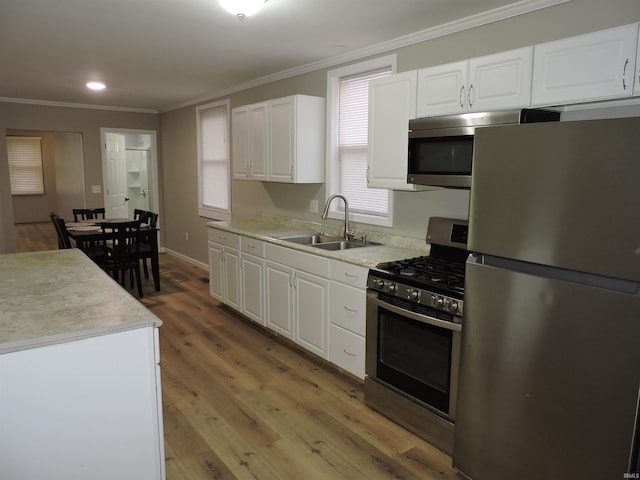 kitchen with stainless steel appliances, light countertops, a sink, and white cabinetry