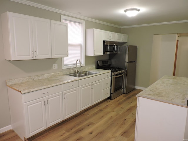 kitchen with appliances with stainless steel finishes, white cabinets, light countertops, and a sink