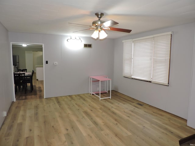 spare room featuring light wood-style floors, visible vents, and ceiling fan