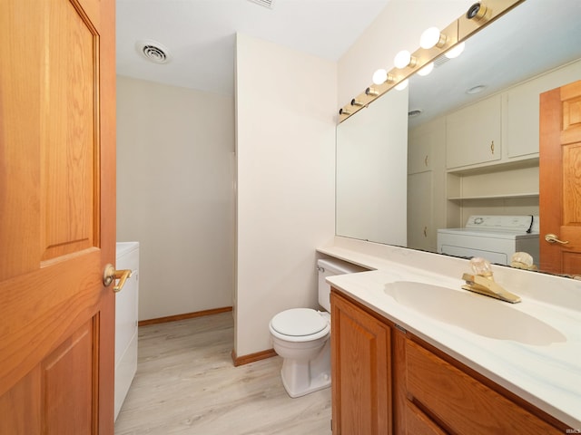 bathroom featuring washer and clothes dryer, visible vents, toilet, vanity, and wood finished floors