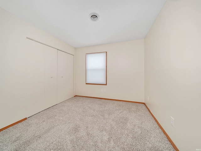 carpeted spare room featuring baseboards and visible vents