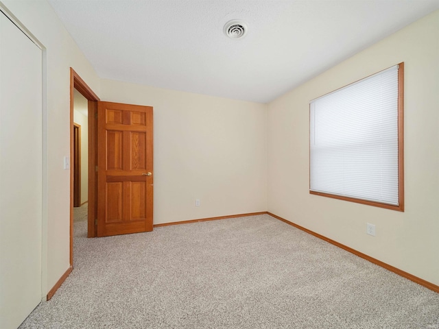 empty room featuring baseboards, visible vents, and light colored carpet