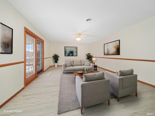 living area featuring baseboards, visible vents, french doors, and light wood finished floors