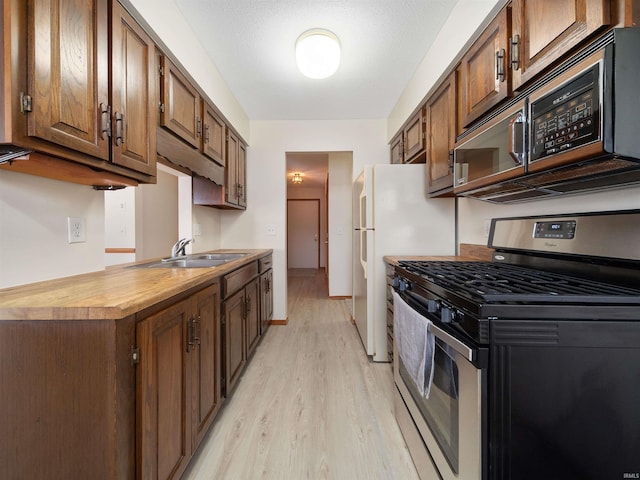 kitchen with light wood-style flooring, baseboards, a sink, and gas stove