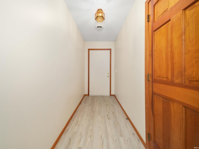 corridor with light wood finished floors and baseboards