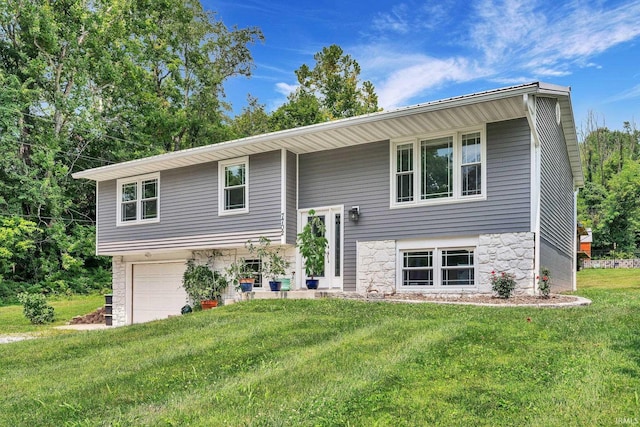 split foyer home with an attached garage, stone siding, and a front yard