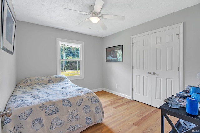 bedroom featuring baseboards, ceiling fan, wood finished floors, a textured ceiling, and a closet