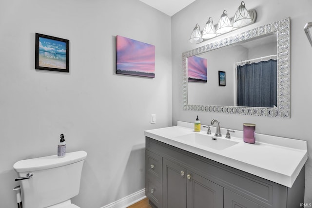 bathroom with vanity, toilet, and baseboards