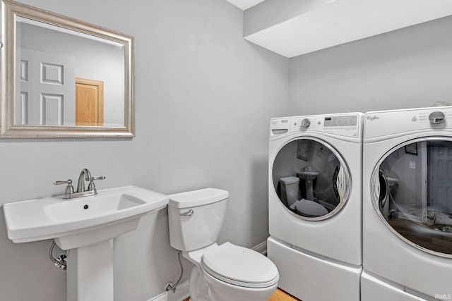 bathroom featuring a sink, independent washer and dryer, and toilet