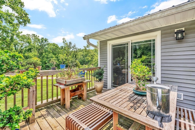 wooden deck with outdoor dining area and a lawn