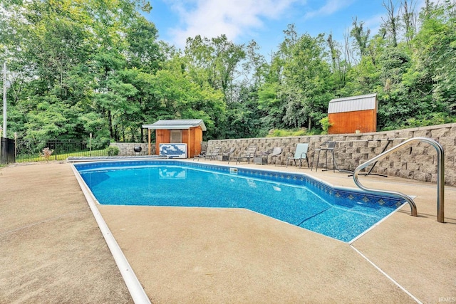 view of pool featuring a storage shed, fence, a fenced in pool, and an outbuilding