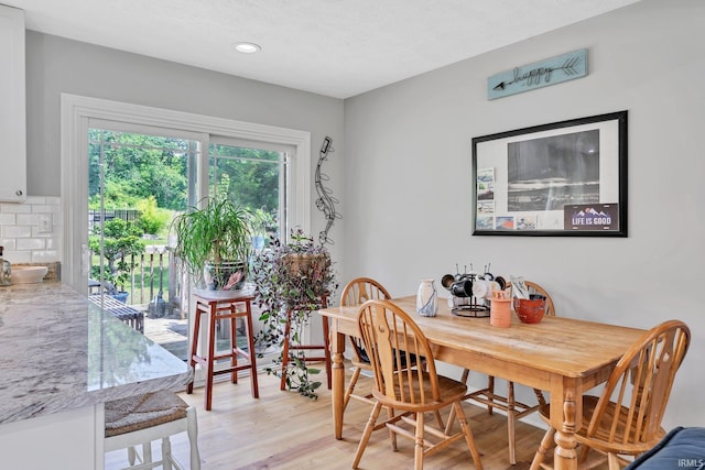 dining area featuring light wood-type flooring and a textured ceiling