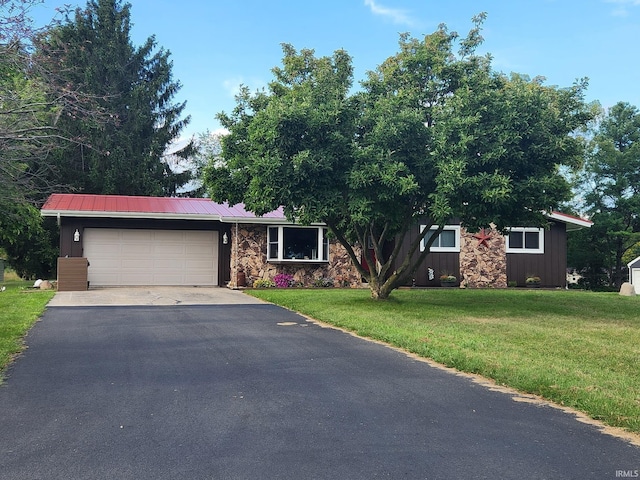 view of front of house with driveway, a garage, metal roof, a front lawn, and board and batten siding