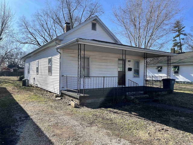 view of front of property featuring covered porch, a chimney, and cooling unit