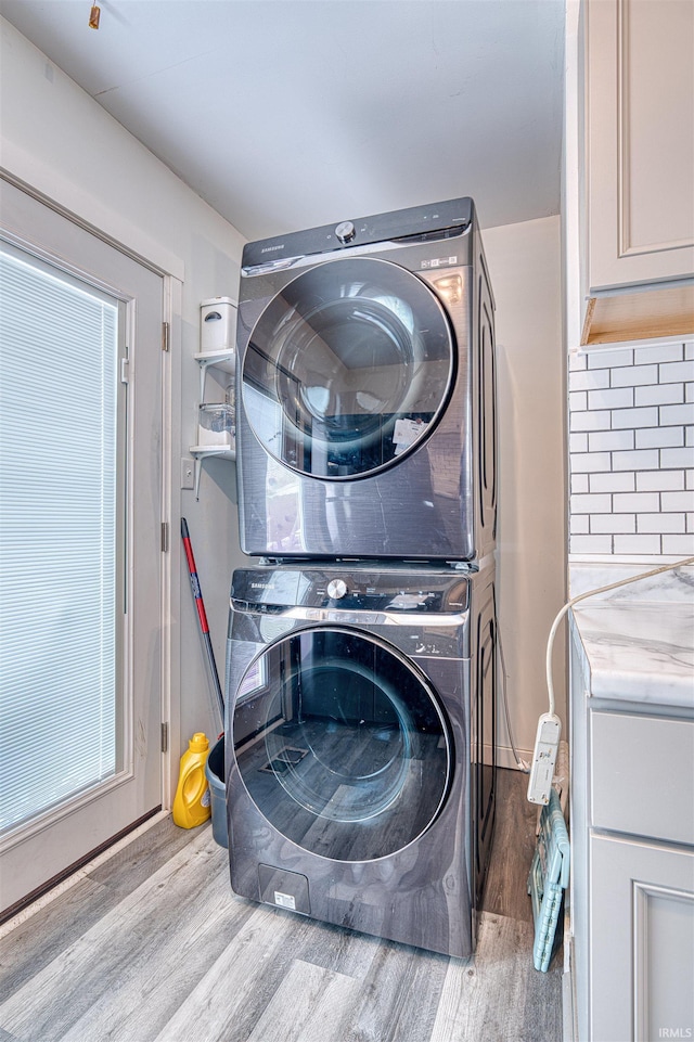 clothes washing area featuring stacked washer and dryer and light wood-style floors