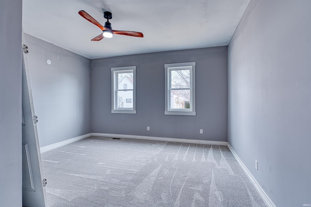 empty room with carpet floors, visible vents, ceiling fan, and baseboards