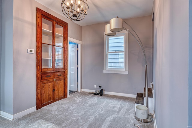 interior space featuring carpet floors, an inviting chandelier, and baseboards