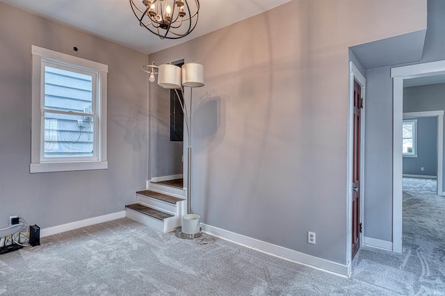 stairs featuring an inviting chandelier, baseboards, and carpet flooring