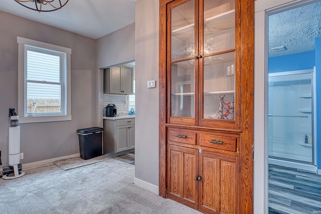 kitchen with light colored carpet, baseboards, light countertops, decorative backsplash, and brown cabinets