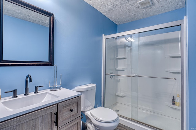 bathroom with a textured ceiling, toilet, visible vents, vanity, and a stall shower