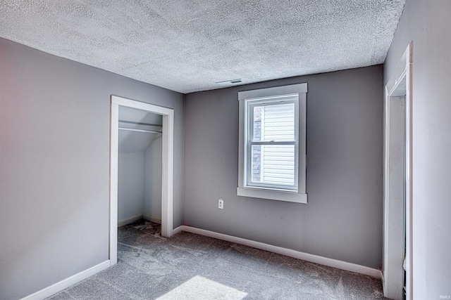 unfurnished bedroom with visible vents, baseboards, a textured ceiling, carpet flooring, and a closet