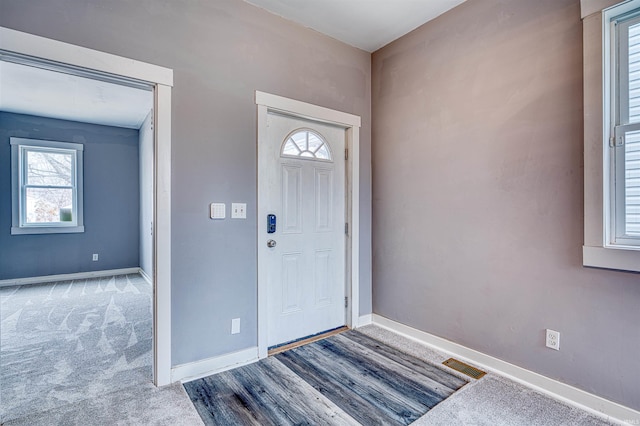 carpeted foyer with visible vents and baseboards