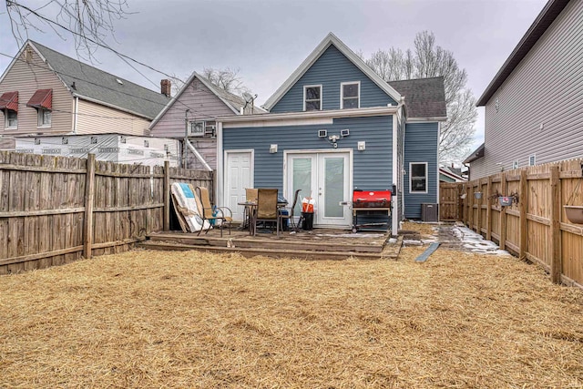 back of property with french doors, a fenced backyard, and roof with shingles