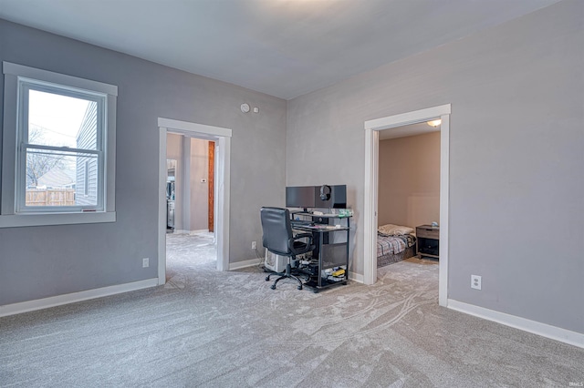 unfurnished office featuring light carpet and baseboards